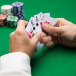 casino, gambling, poker, people and entertainment concept - close up of poker player with playing cards and chips at green casino table