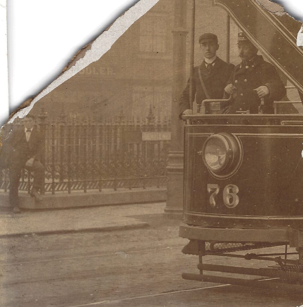 Tram 76 with driver, conductor and background gent in front of the 'gents'