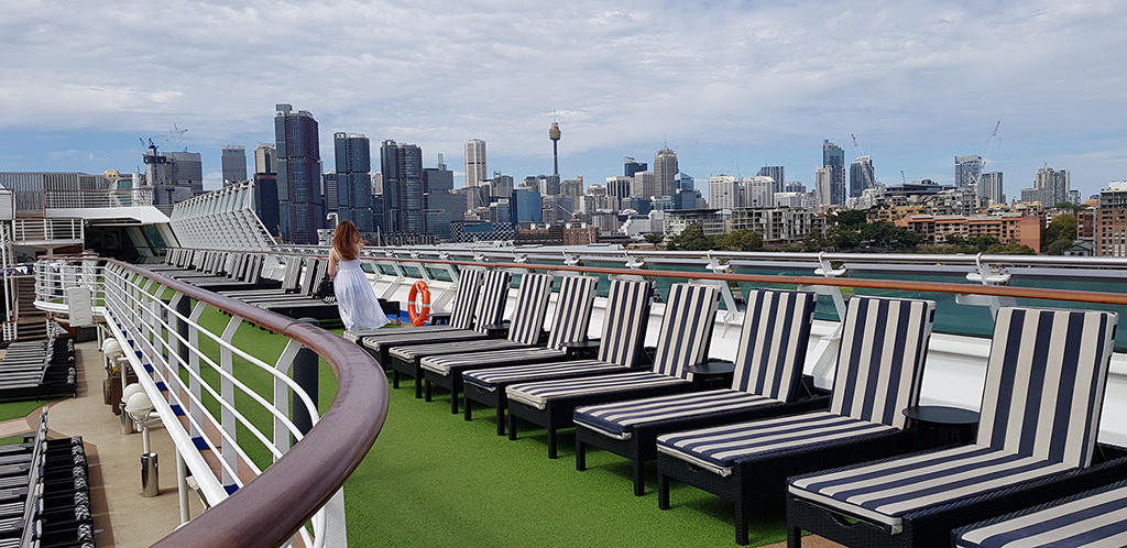 Deck chairs on cruise ship with Sydney skyline behind by Jennifer Mosher - thumbnail